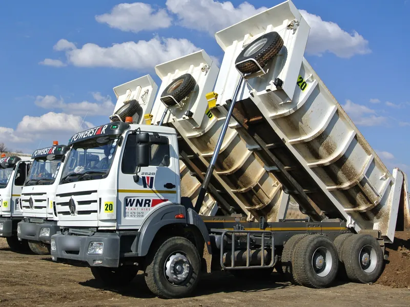 Three white WNR Plant Hire tipper trucks lined up with their bins raised
