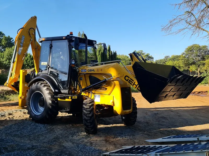 Yellow WNR TLB backhoe loader on site with its front bucket raised