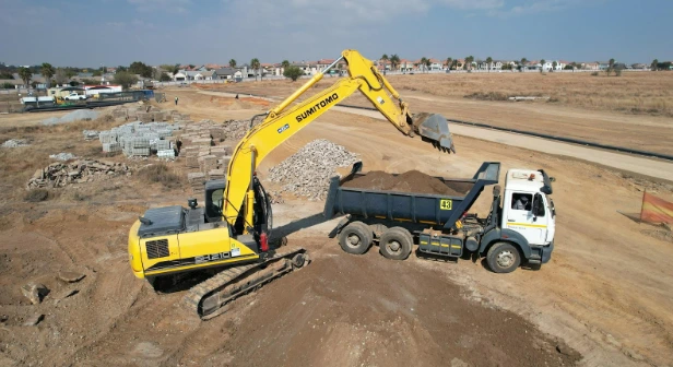 Excavator loading a tipper truck on a large site
