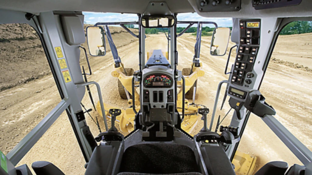 View from a grader cab over the blade onto a dirt road